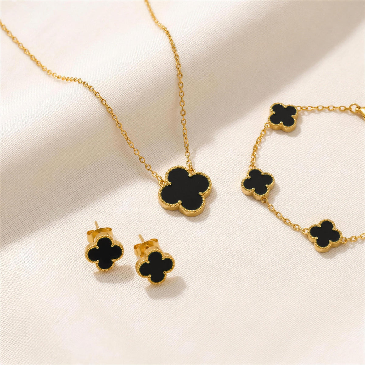 The Clover Set in black: necklace, bracelet and studs on ivory linen
