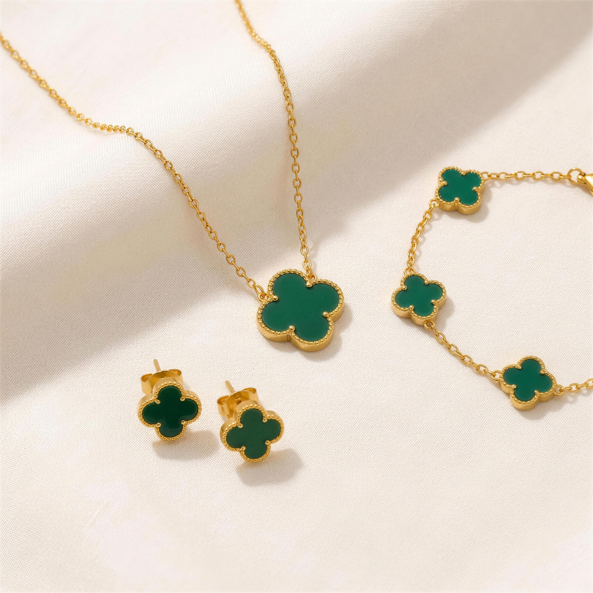 The Clover Set in green: necklace, bracelet and studs on ivory linen