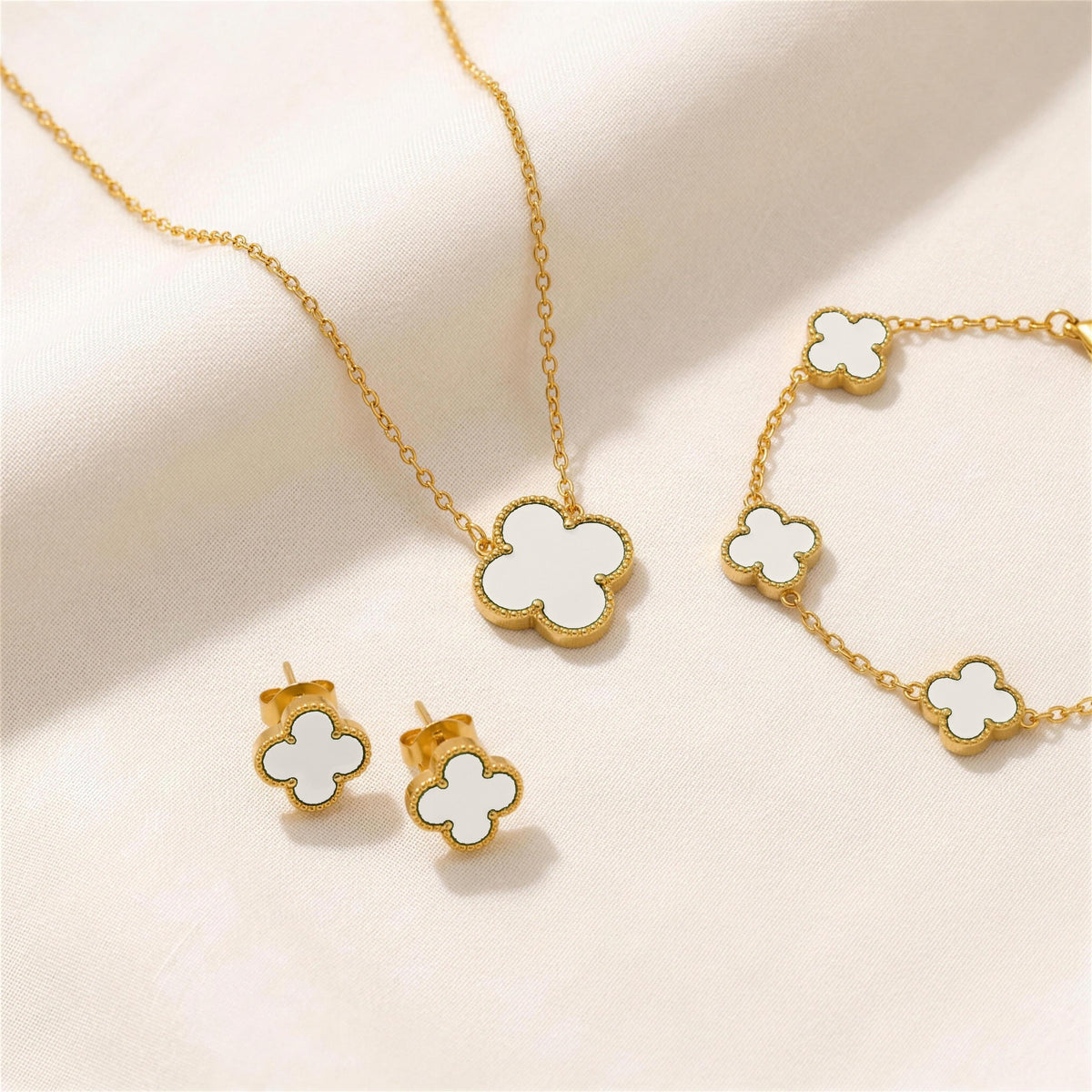 The Clover Set in white: necklace, bracelet and studs on ivory linen